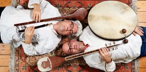 Kees Posthumus en Henk van Glabbeek. Liggend op een tapijt met oosterse instrumenten in de hand.